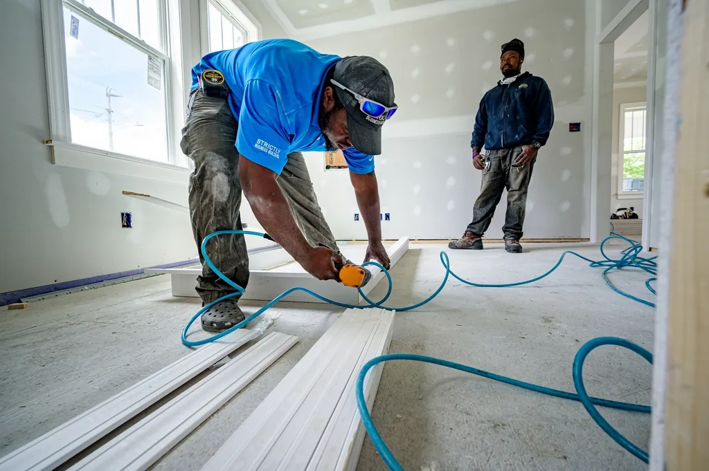 Tradesman installing trim in a room under construction